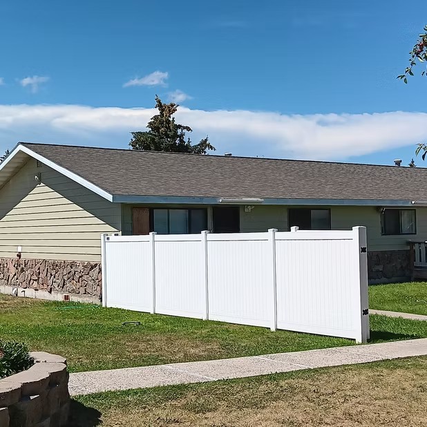 Light-colored home behind a white fence