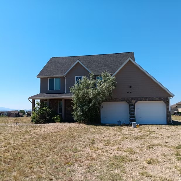 Two-story home with masking on garage doors